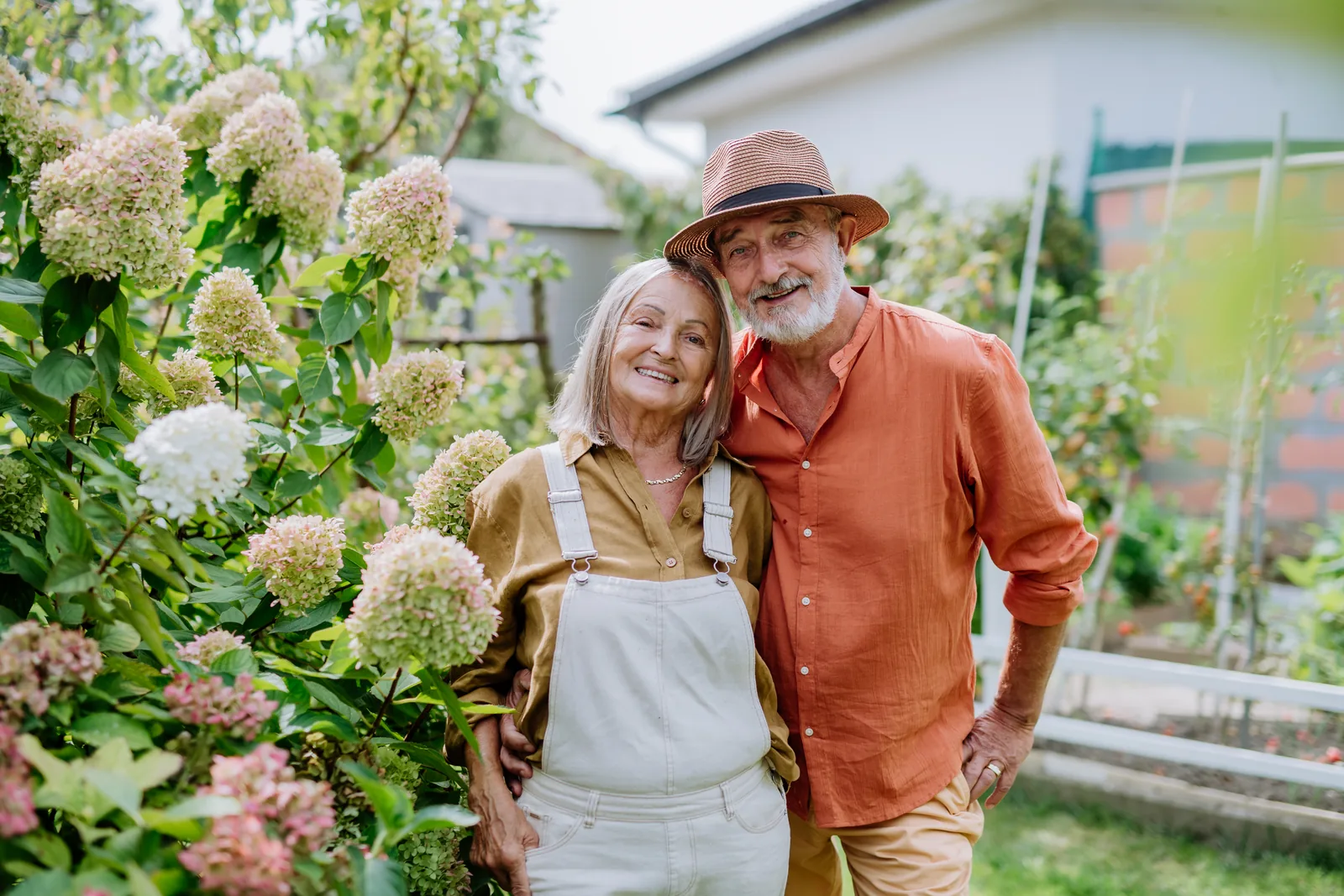Taux rachat de crédit : un couple de retraités souriants dans son jardin